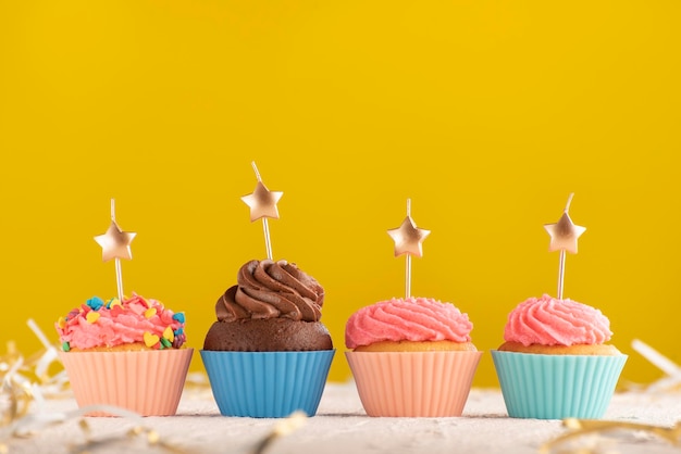 Cupcakes con velas doradas en forma de estrellas sobre fondo amarillo brillante. Fondo festivo. Copie el espacio.