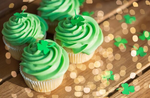 cupcakes verdes e trevo em mesa de madeira