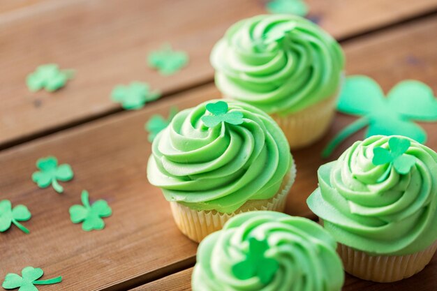 cupcakes verdes e trevo em mesa de madeira