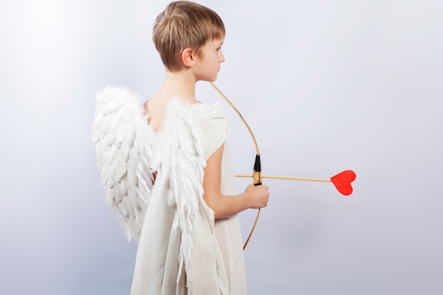 Cupido menino com asas e um arco de tiro, no final da flecha um coração vermelho.