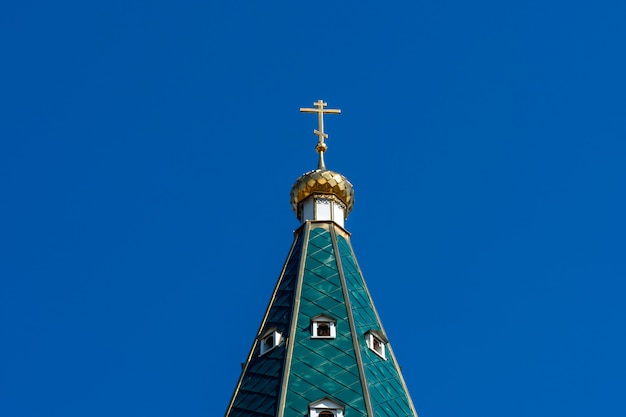 Cúpula dourada com uma cruz no telhado verde da igreja ortodoxa russa