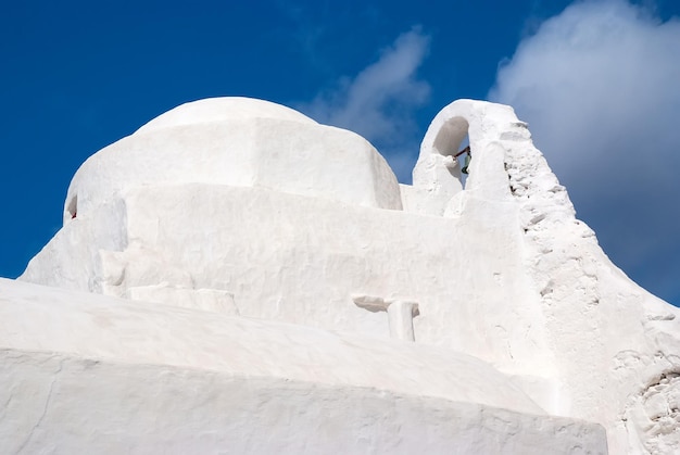 Cúpula e torre sineira da igreja panagia paraportiani em mykonos, grécia. arquitetura de construção de capela. igreja branca no céu azul nublado. religião e conceito de culto. férias na ilha mediterrânea.