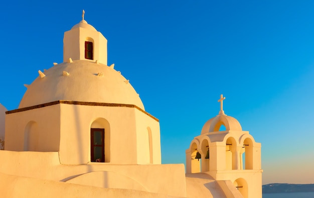 Cúpulas de la iglesia griega en la isla de Santorini a la luz del sol del atardecer, Grecia