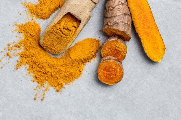 Curcuma ou raiz de curcumina açafrão em pó e açafrão fresco em fundo de concreto especiaria coloração natural medicina alternativa vista superior