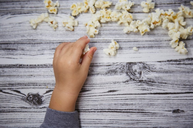 La curiosidad de Baby39s La mano del niño prueba una palomita de maíz Concepto del Día Nacional de las Palomitas de maíz Espacio de copia Vista superior