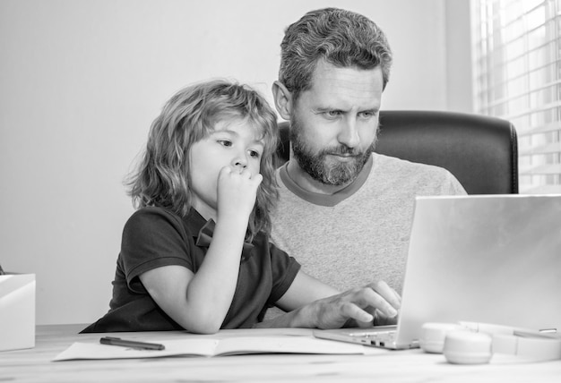 Curioso padre e hijo en la escuela trabajando en línea en un seminario web para portátiles