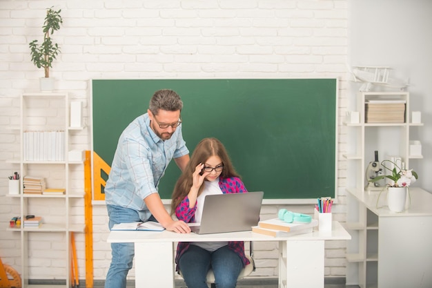 Curioso pai e filho estudam na escola com laptop no fundo do quadro-negro de volta à escola