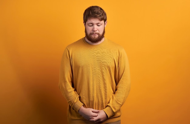 Curioso trabalhador do sexo masculino com a barba por fazer focado olha com interesse como percebe que algo se pergunta estar em camiseta branca e óculos redondos posa sozinho contra um fundo branco expressões faciais