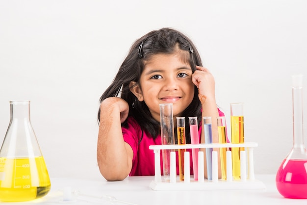 Curiosos escolares indios o científicos que estudian ciencias, experimentando con productos químicos o microscopio en el laboratorio, enfoque selectivo