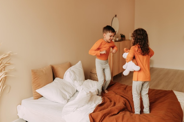 Foto curiosos niños felices hermano y hermana en pijama jugando divirtiéndose en un dormitorio acogedor en casa