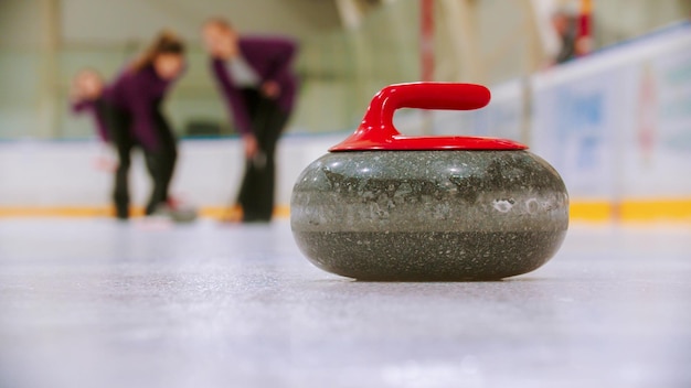 Curling una piedra de granito con mango rojo en el campo de hielo