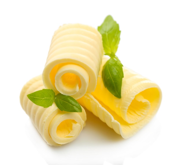 Curls de mantequilla fresca con albahaca aislada en blanco