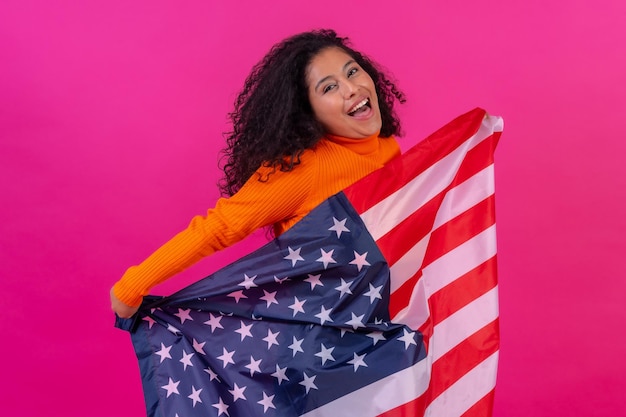 Curlyhaired Frau mit der USA-Flagge auf einer rosa Hintergrundatelieraufnahme