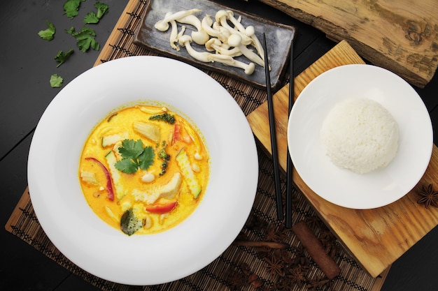 Curry amarillo con pollo en un gran plato blanco, arroz y palillos.