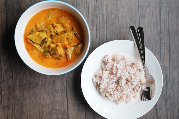 Curry de calabaza en el tazón blanco sobre mesa de madera