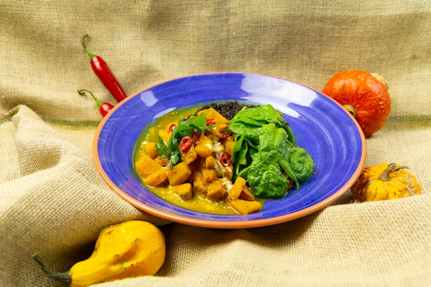 Curry com frango de manga e lentilhas pretas, em prato azul