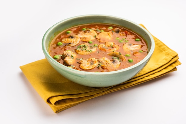 Curry de cogumelos e ervilha com comida indiana de alho assado servido em uma tigela