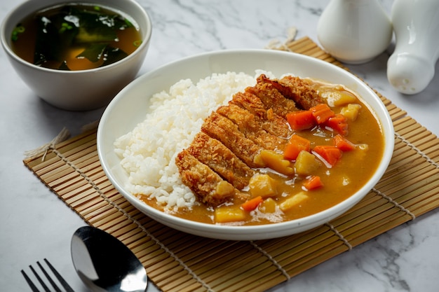 Curry de costeleta de porco frito com arroz na superfície escura