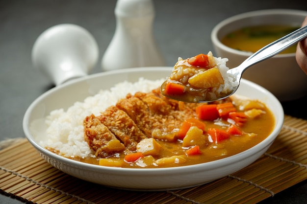 Curry de costeleta de porco frito com arroz na superfície escura