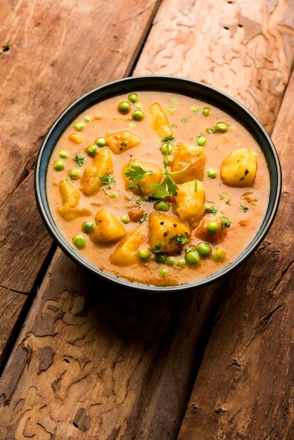 Curry indio Aloo Mutter: patatas y guisantes sumergidos en salsa de tomate y cebolla y adornados con hojas de cilantro. Servido en un Karahi o Kadhai o en una sartén o tazón