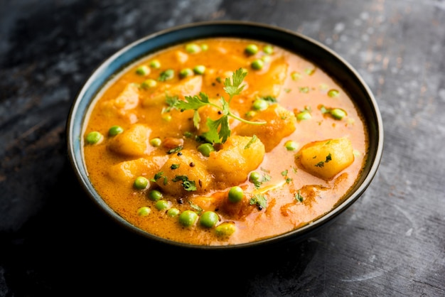 Curry indio Aloo Mutter: patatas y guisantes sumergidos en salsa de tomate y cebolla y adornados con hojas de cilantro. Servido en un Karahi o Kadhai o en una sartén o tazón