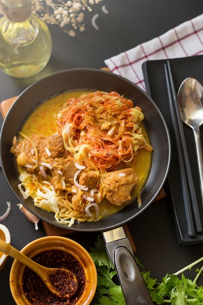 Curry Nudelsuppe mit würziger Kokosmilch und Rindfleisch In einer schwarzen Pfanne Auf einem schwarzen Holztisch