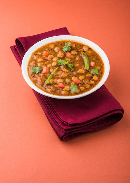 Curry picante de Chick Peas, prato indiano, também conhecido como Chola ou Chana Masala ou comumente Chole, servido com puri ou poori frito sobre fundo colorido ou de madeira. Foco seletivo