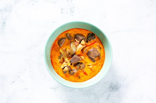 Curry de pollo, masala de curry de pollo rojizo picante, con un trozo de pierna prominente, servido en un bol