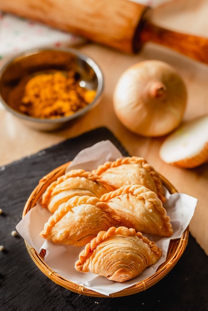 Curry Puff auf einem dunklen Teller und Zutaten