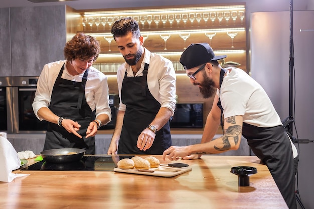 Curso de cocina chef masculino senior en uniforme de cocinero enseña a los jóvenes estudiantes de clase de cocina a preparar y mezclar ingredientes para platos en la cocina del restaurante