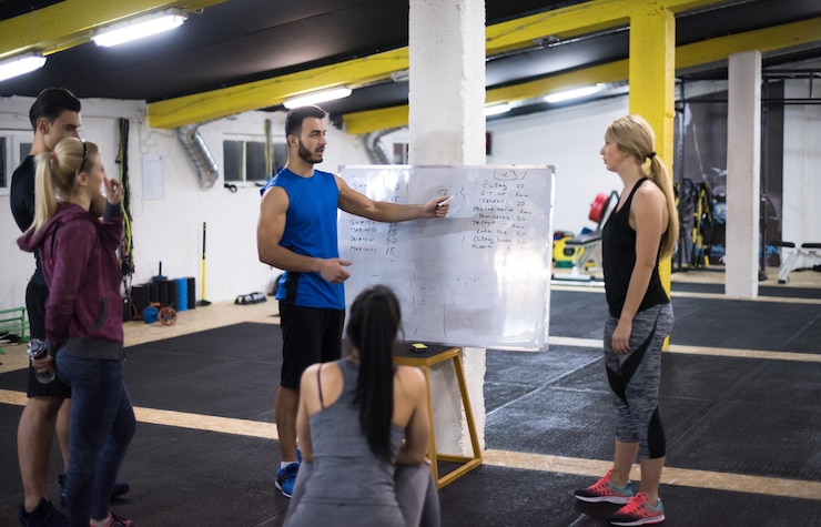 Foto curso de treinamento.grupo de jovens atletas recebendo instruções do treinador antes do exercício no ginásio cross fitness