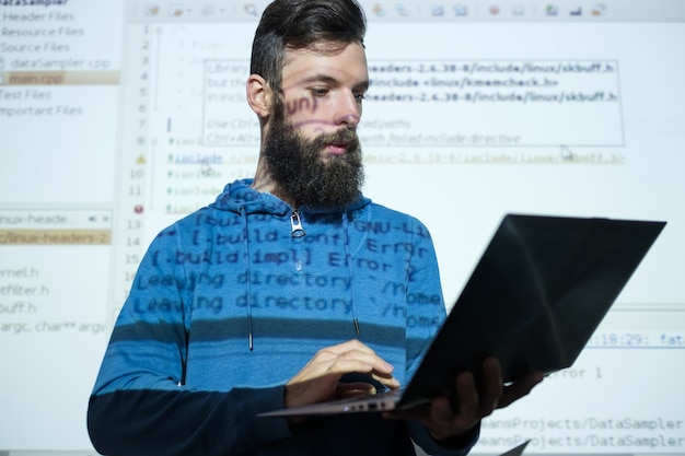 Foto cursos de programador no centro de educação homem segurando um laptop enquanto dá uma palestra