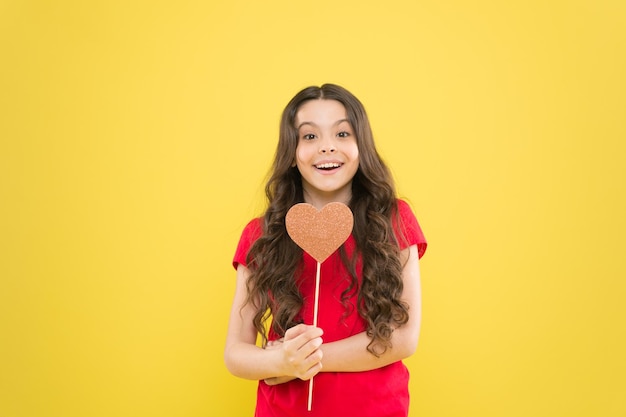 Curta e apoie o dia dos namorados Apaixone-se O amor salvará o mundo Garoto promovendo o amor Atitude pessoal Humor alegre eu te amo Menina criança sorrindo segure o símbolo do coração na vara