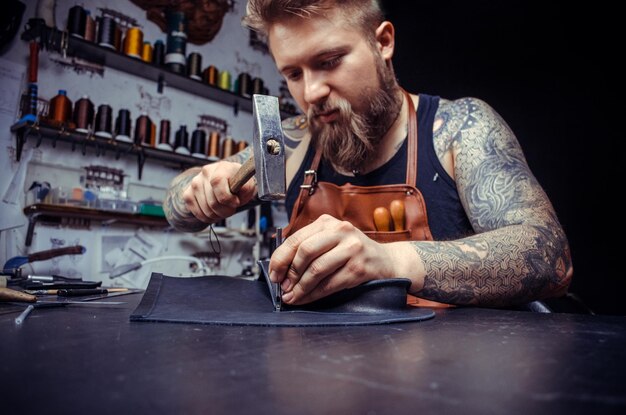 curtidor de cuero cortando formas de cuero para un nuevo producto en su tienda de curtido