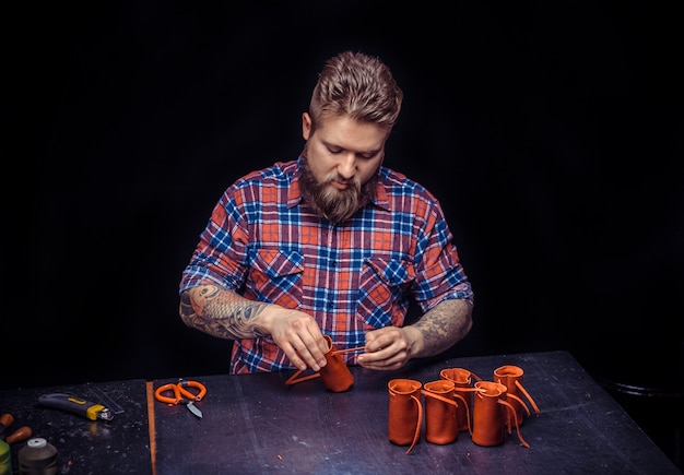 Curtidor de cuero realiza trabajos de cuero para un nuevo producto en el estudio de cuero. / Artesano que trabaja como artesano en su lugar de trabajo.