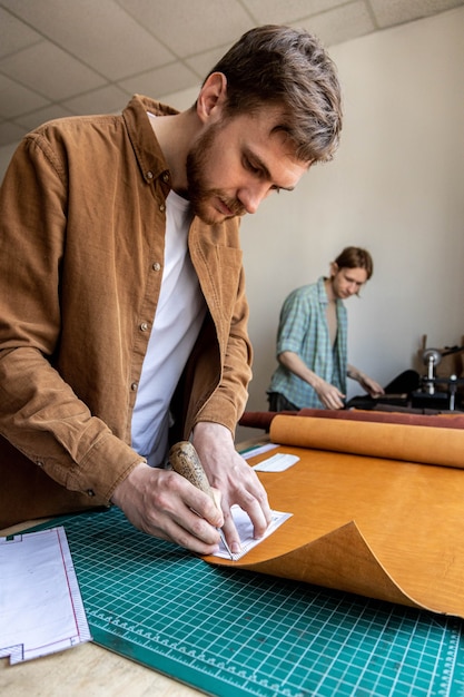 Curtidor masculino haciendo esquema de corte de bolsa trabajando en el taller de cuero creación artesanal