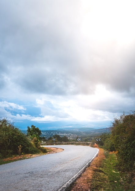 Curva de uma estrada secundária em uma paisagem montanhosa em um dia nublado de outono. Foto vertical
