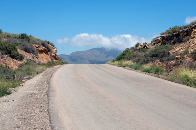 Curvando a estrada do deserto para cima com vista para as montanhas e o céu dramático