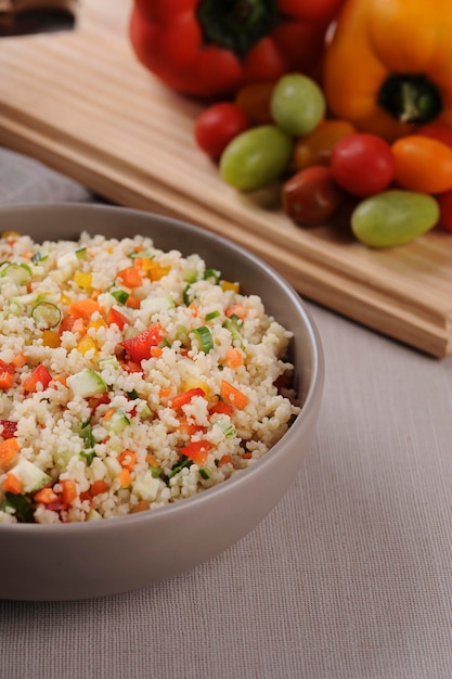 Cuscús con verduras en un bol rústico rodeado de tomates pimientos y un vaso de aceite de oliva Cuscús marroquí Enfoque selectivo