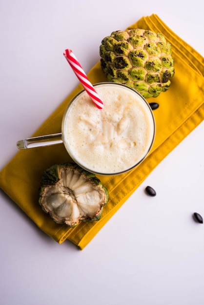 Custard Apple oder Sitafal Milk Shake serviert in einem Glas mit ganzen Früchten auf stimmungsvollem Hintergrund. Selektiver Fokus