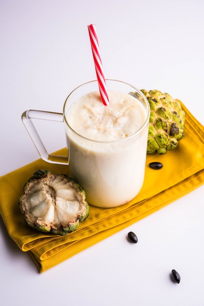 Custard Apple oder Sitafal Milk Shake serviert in einem Glas mit ganzen Früchten auf stimmungsvollem Hintergrund. Selektiver Fokus