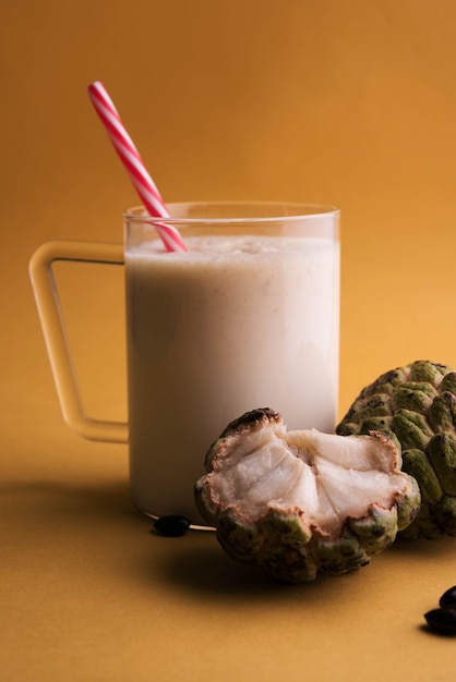 Custard Apple ou Sitafal Milk Shake servido em um copo com frutas inteiras sobre um fundo temperamental. Foco seletivo