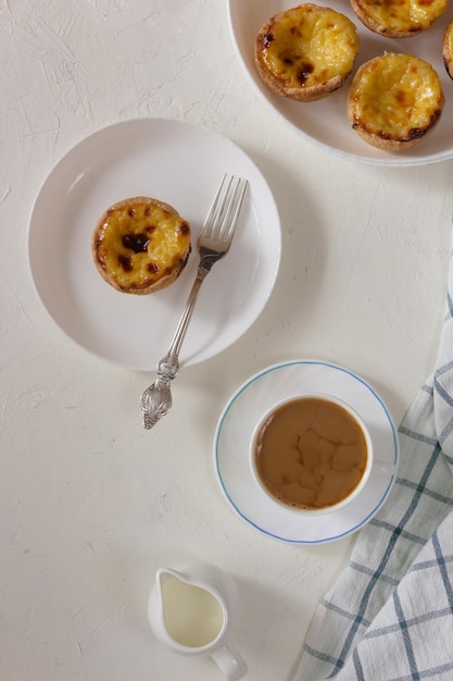 Custard Tart Pastel de Nata oder Pastel de Belem auf dem weißen Teller mit einer Tasse Kaffee und Milch i