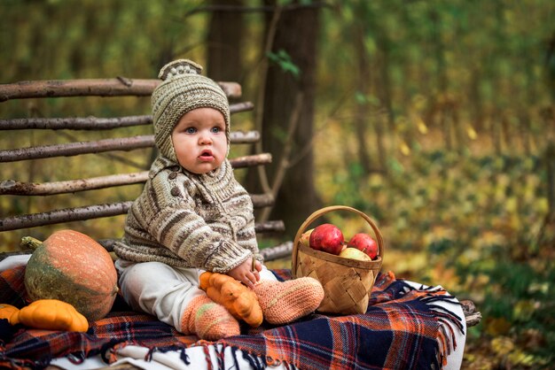 Cute Baby Boy con calabazas sentado en un banco de madera