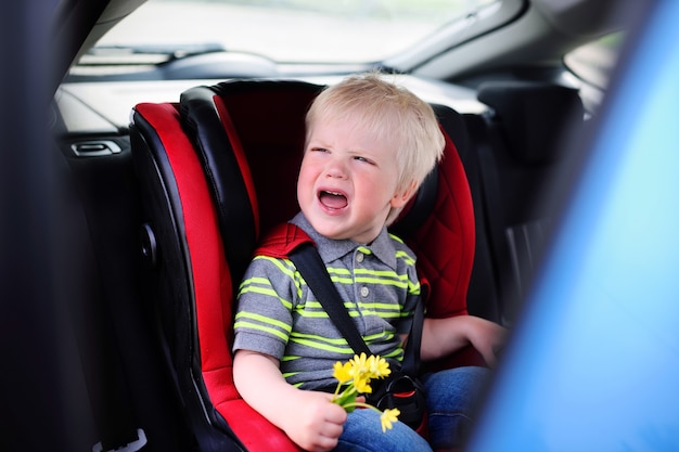 Cute Baby Boy rubias llorando en un asiento de coche para niños