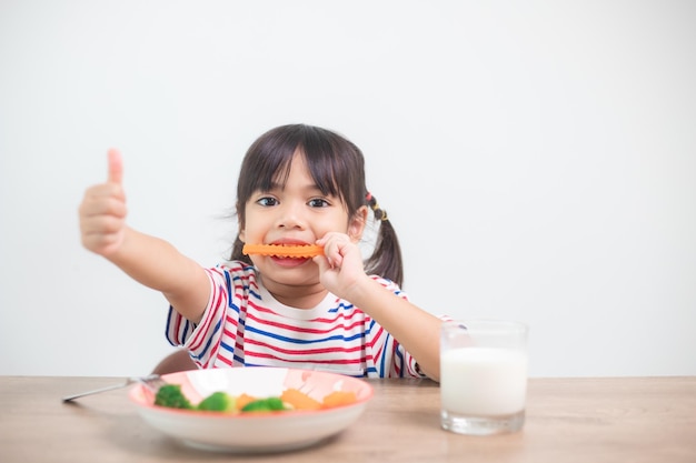 Cute, criança asiática, menina, comer, legumes saudáveis, e, leite, para, dela, refeição