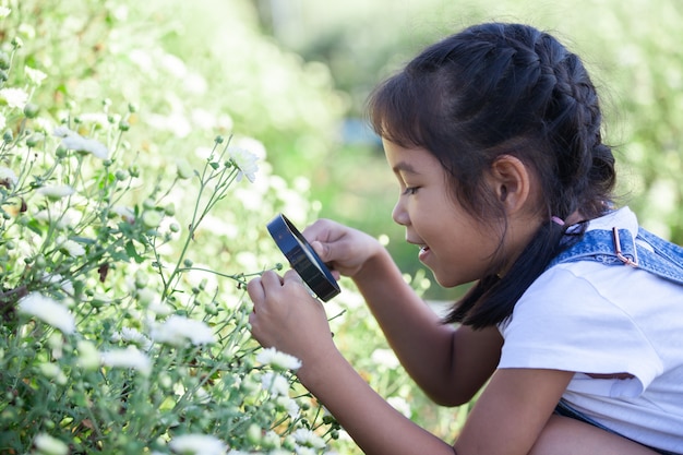 Cute, criança asiática, menina, olhar, bonito, flor, através, um, lupa, em, a, campo flor