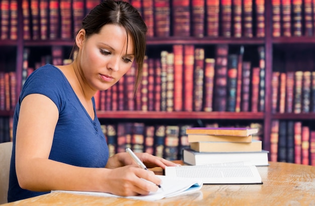 Cute girl writing on notebook in library