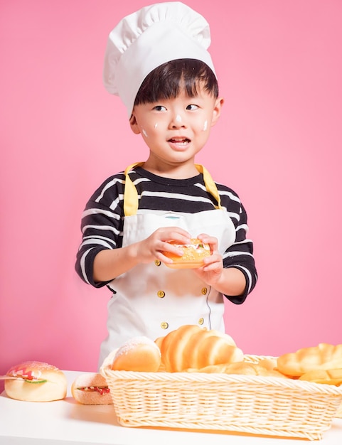 Cute Junge hält Brot und weint, während er vor rosa Hintergrund steht