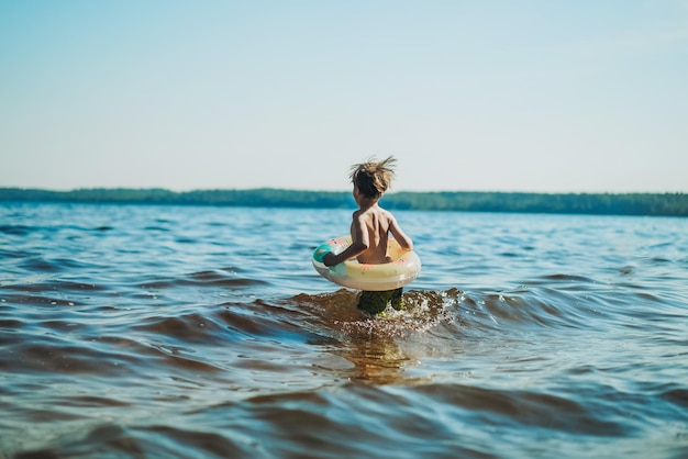 Cute kaukasischen Jungen laufen ins Wasser mit Spritzern und Lachen Urlaub am Meer Glückliche Kindheit Bild mit selektiven Fokus